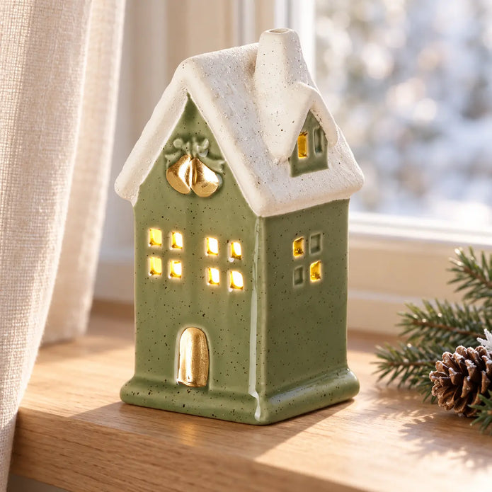 Sage green LED light up ceramic house on winter windowsill
