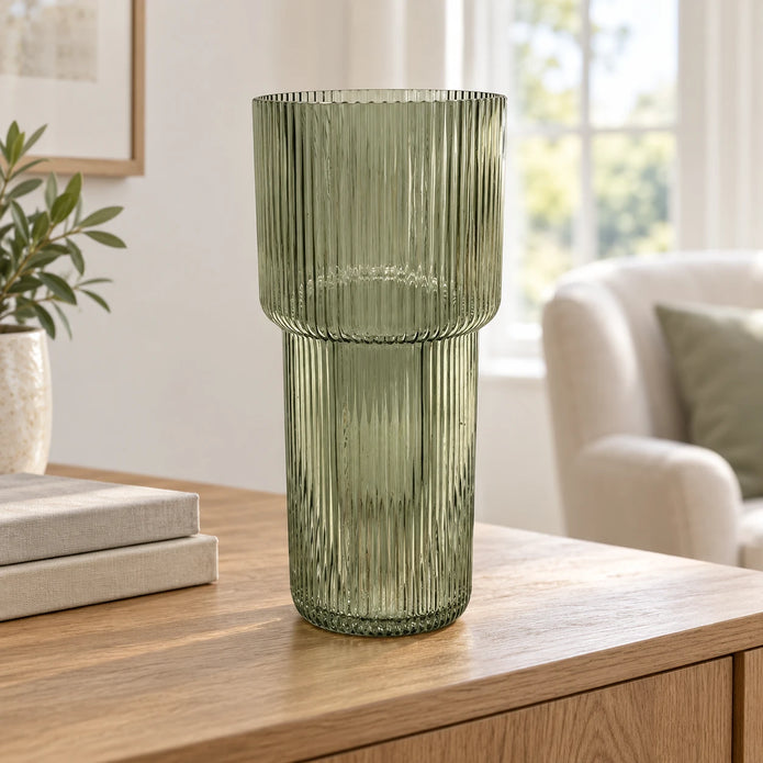Satchville sage green tall ribbed glass vase on a sideboard, showcasing its elegant, textured design and slender shape.