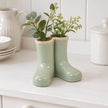 Satchville small sage green ceramic Wellington boot vase with foliage on a dresser