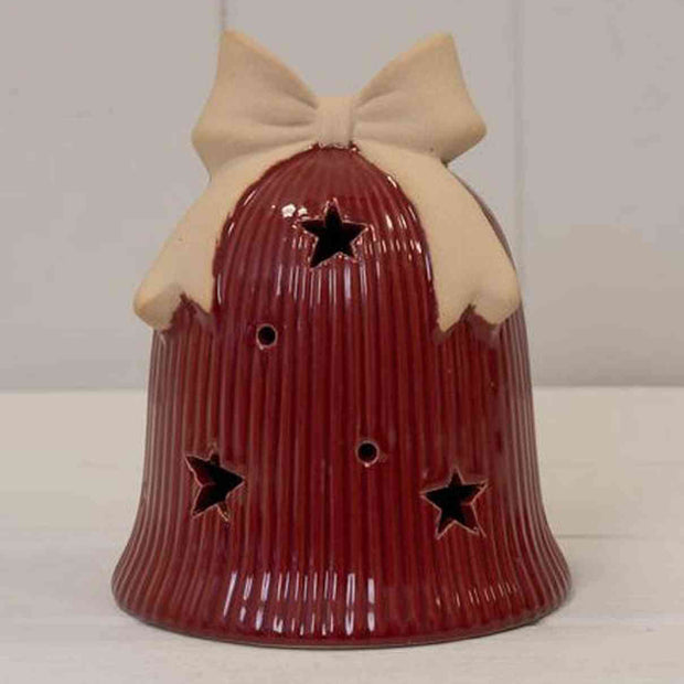 Red ceramic bell with a beige bow on a white surface and light gray background
