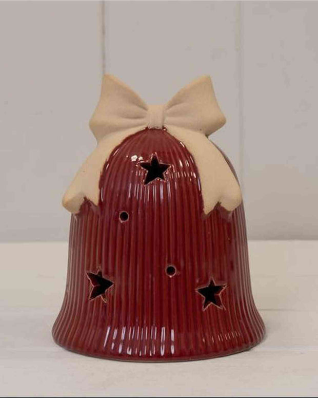 Red ceramic bell with a beige bow on a white surface and light gray background