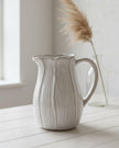 Natural ceramic jug with petal-shaped design, ideal for home decor, by Satchville, featuring elegant, handcrafted floral-inspired details.
