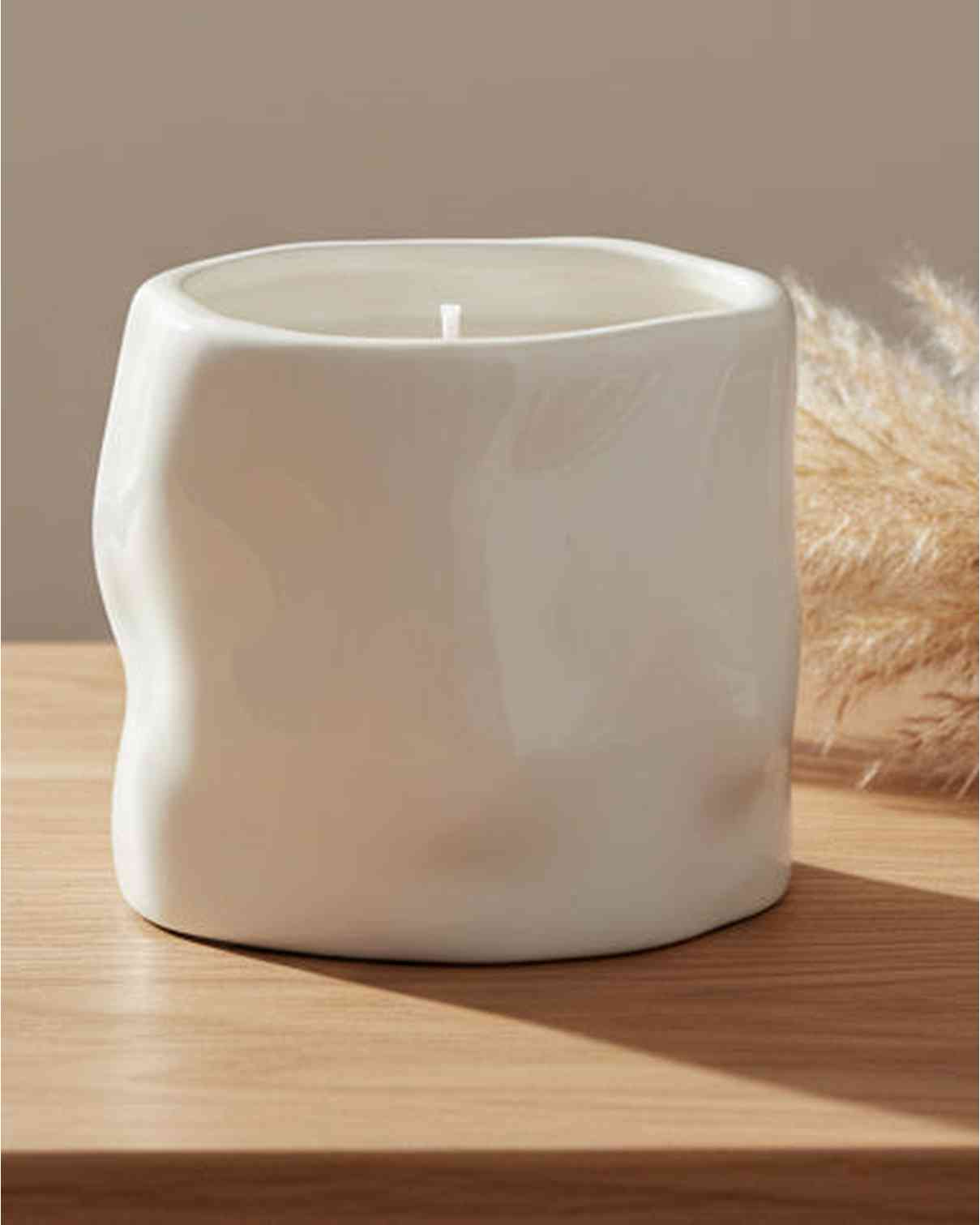 White sculpted candle by Satchville, a stylish home decor piece featuring intricate carvings and a smooth finish.