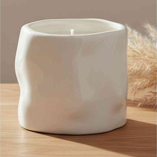 White sculpted candle by Satchville, a stylish home decor piece featuring intricate carvings and a smooth finish.