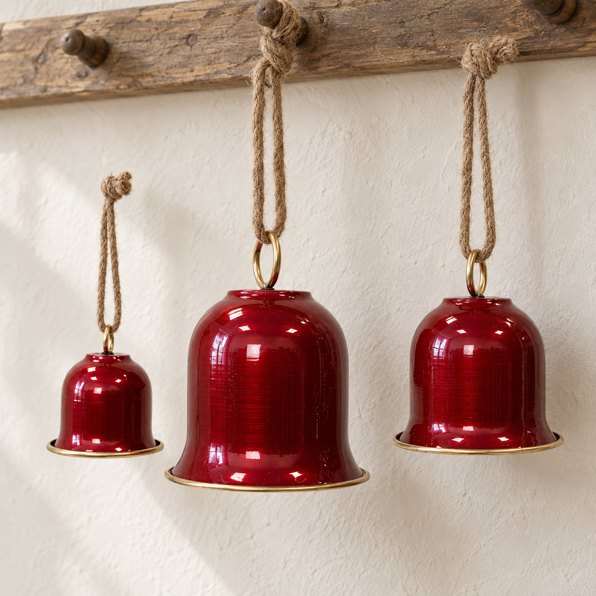Close detail of three glossy red hanging bells with gold rims and jute loops