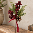 Close detail of red berries, green foliage, pinecone and red ribbon stem