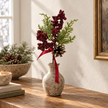 Red berry and ribbon stem styled in a stoneware vase on an oak console