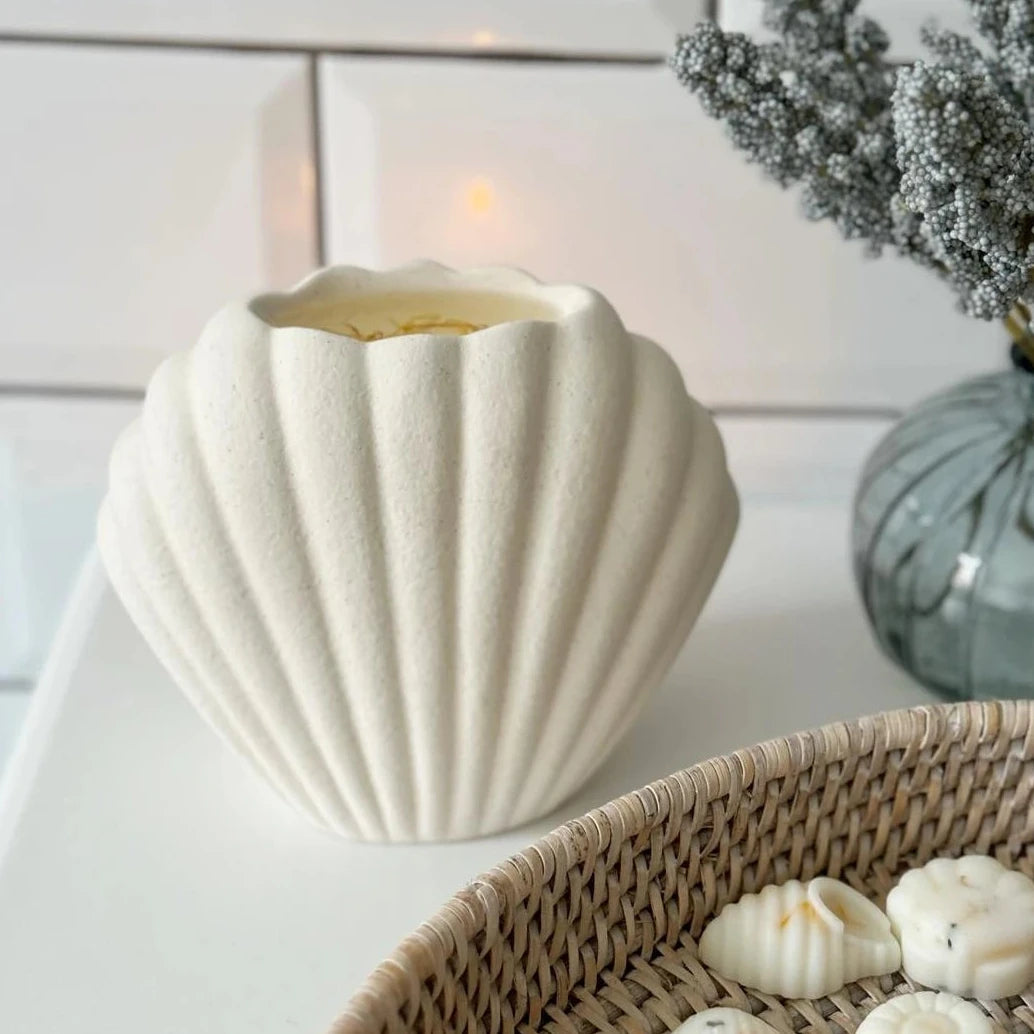 Sea Shell Matte Ceramic Oil Burner and Wax Warmer, cream shell-shaped burner with a lit tealight beside seashells