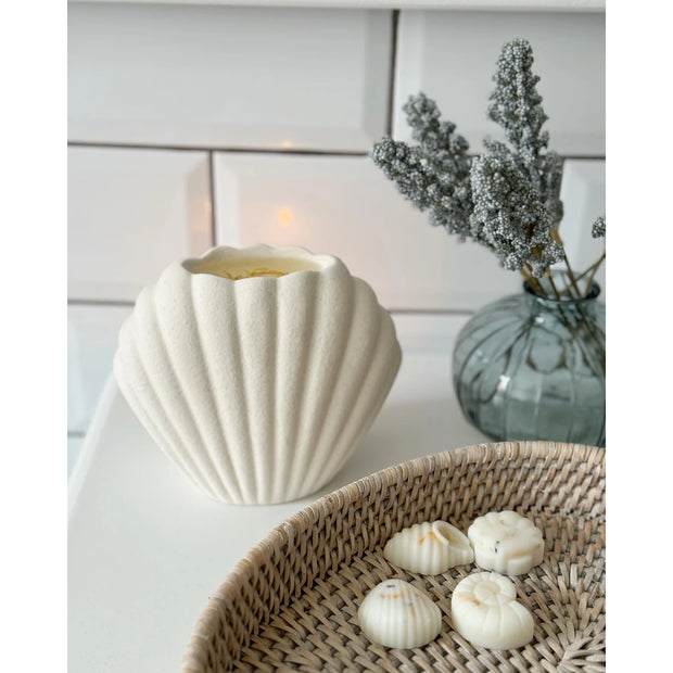 Sea Shell Matte Ceramic Oil Burner and Wax Warmer, cream shell-shaped burner with a lit tealight beside seashells