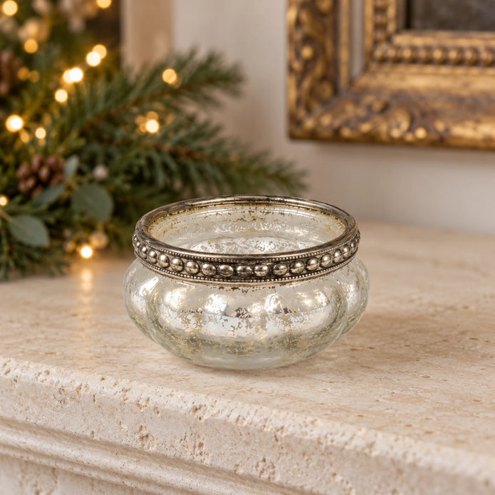 One empty silver mercury glass tealight holder on a festive limestone mantel.