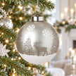 Silver winter scene glass bauble hanging on a Christmas tree