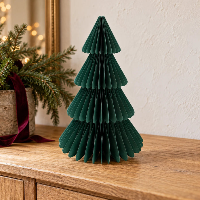Single 36cm green paper Christmas tree on an oak sideboard with festive greenery.