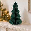 Green paper Christmas tree displayed on a stone mantel.