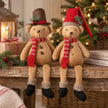 Christmas teddy bears in brown top hat and red knitted hat on rustic shelf with fairy lights