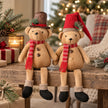 Festive sitting teddy bears with dangling legs, red striped scarves and black boots on a Christmas bench