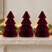 Three equal-sized burgundy paper Christmas trees side by side on a stone mantel.