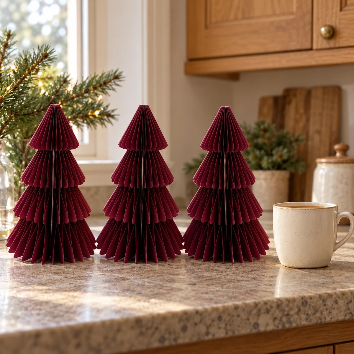 Set of three 20cm burgundy paper trees beside a mug of tea on a kitchen counter.