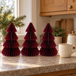 Set of three 20cm burgundy paper trees beside a mug of tea on a kitchen counter.