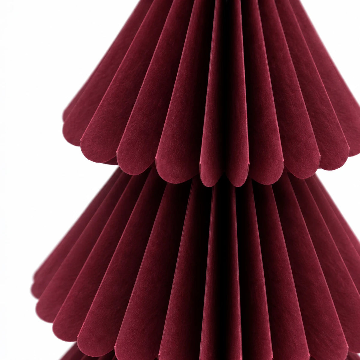 Close-up of burgundy paper folds and scalloped tier edges.