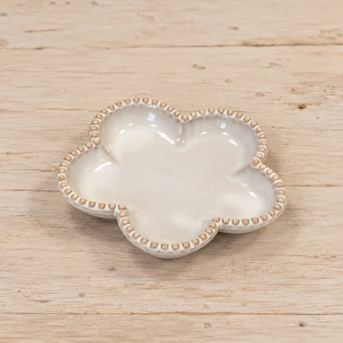 Single small natural ceramic flower plate lying flat on a wooden surface