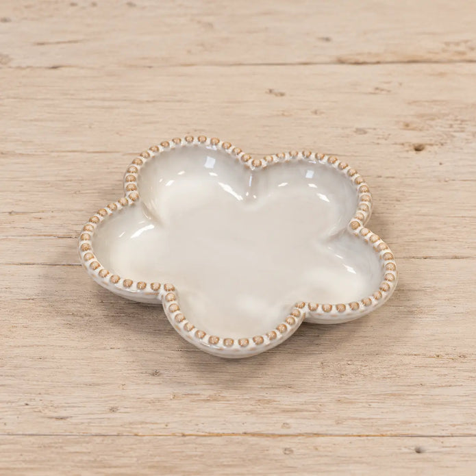 Single small natural ceramic flower plate lying flat on a wooden surface