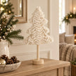 Small cream fluffy tree on an oak console.