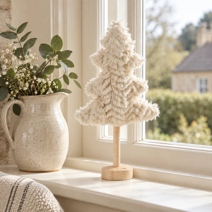 Small cream fluffy tree on a cream windowsill.