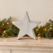 Small pale ceramic star on limestone mantel with evergreen garland
