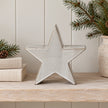 Small glazed ceramic star on shelf beside cream books and pine foliage