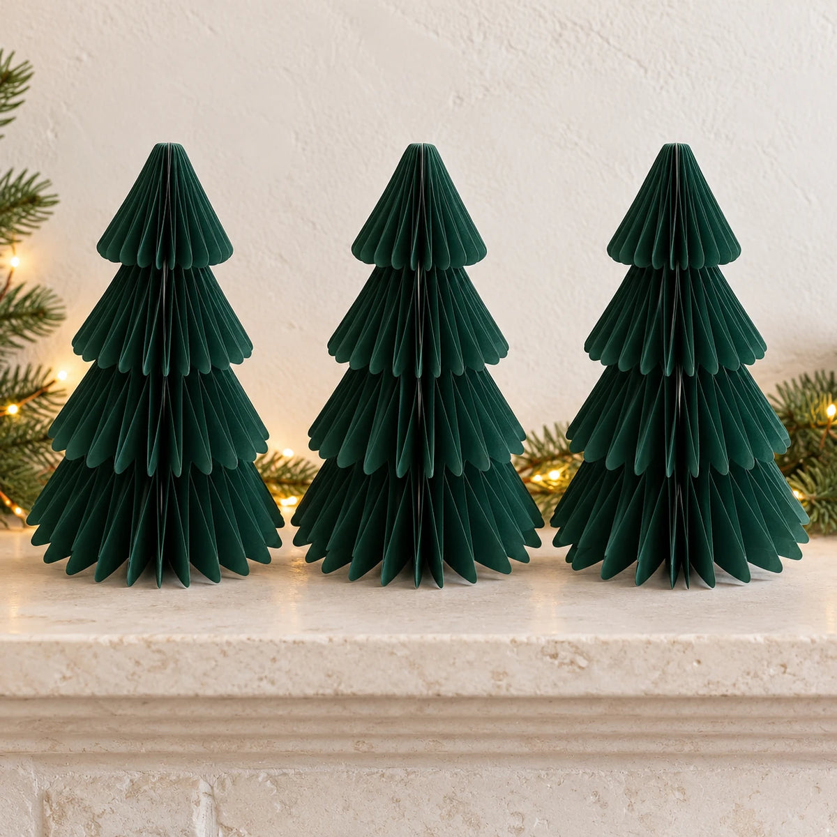 Three equal-sized green paper Christmas trees side by side on a stone mantel.