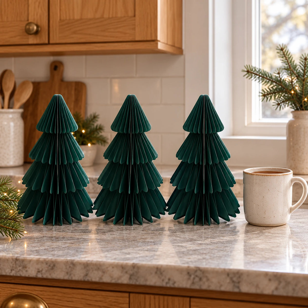 Set of three 20cm green paper trees beside a mug of tea on a kitchen counter.