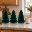 Set of three 20cm green paper trees beside a mug of tea on a kitchen counter.