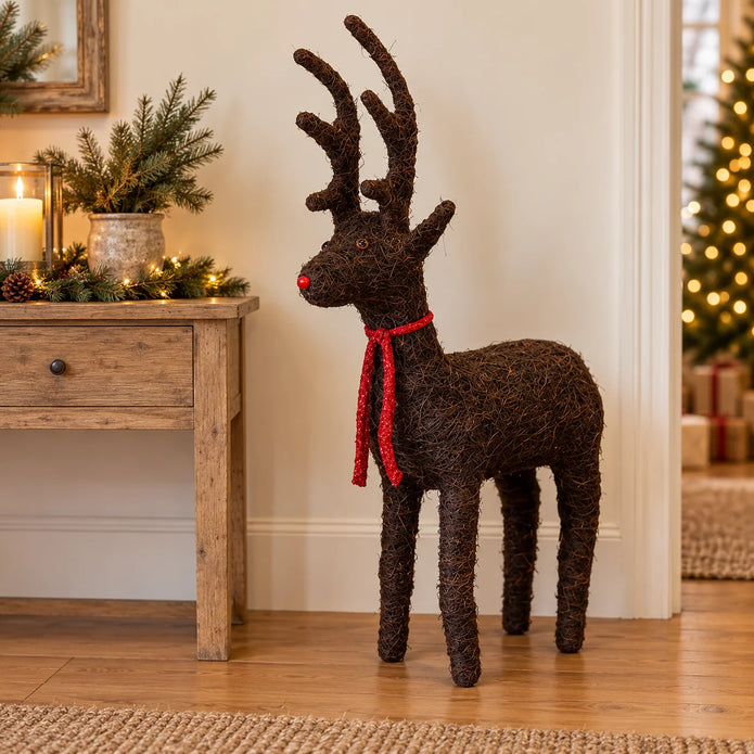 Small standing Salim deer with a red ribbon bow beside a festive console