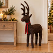 Small standing Salim deer with a red ribbon bow beside a festive console
