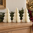 Three matching 20cm winter white paper Christmas trees on an oak sideboard with festive greenery.