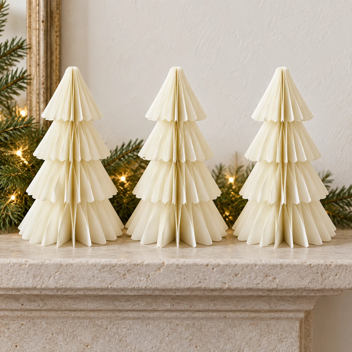 Three equal-sized winter white paper Christmas trees side by side on a stone mantel.