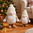 Medium and large snowy white gonks beside a Christmas tree.