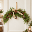 Red berry Christmas swag with pinecones and hessian bow on a bright country home wall