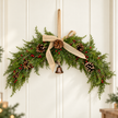 Red berry spruce Christmas arched swag with hessian bow styled on a cream panelled wall