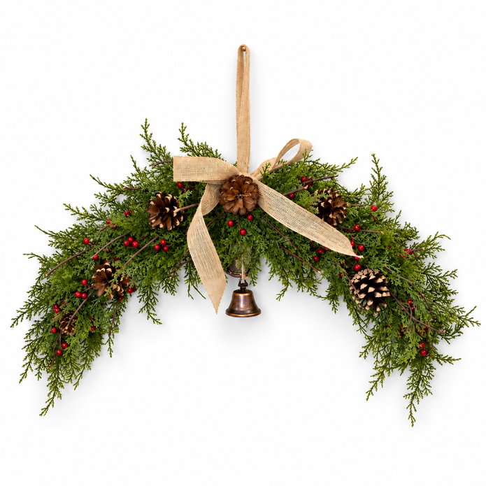 Spruce arched Christmas swag with red berries, pinecones, hessian bow and hanging bell on white background
