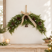 White berry spruce arched Christmas swag styled above rustic wooden console in a bright country home