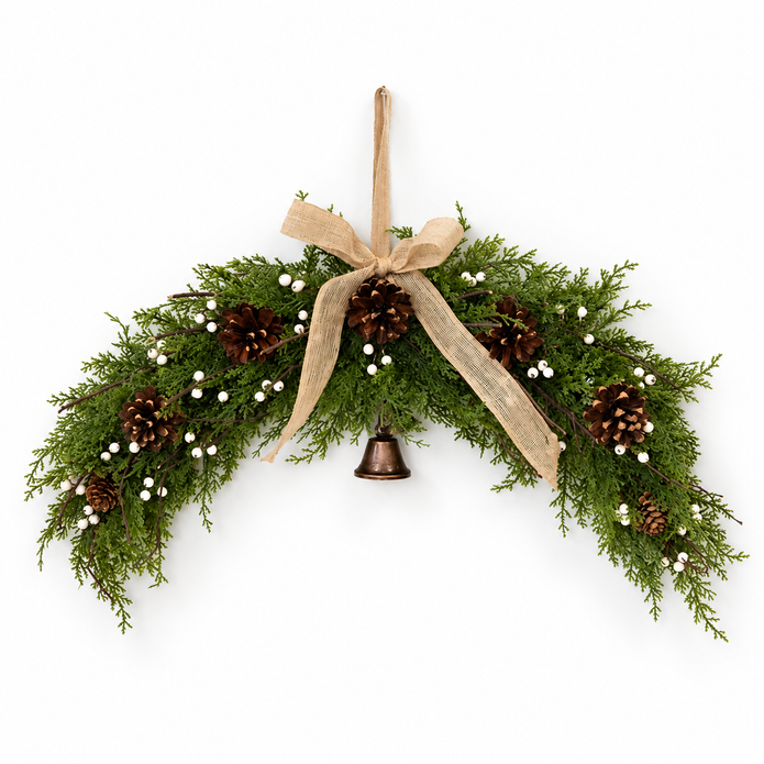 Spruce arched Christmas swag with white berries, pinecones, hessian bow and hanging bell on white background