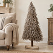 Standing white and natural twig tree beside a linen armchair.