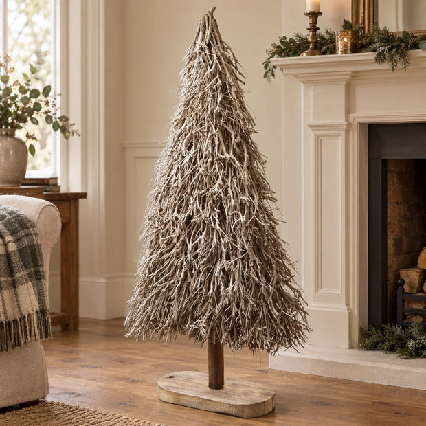 Standing white and natural twig tree beside a cream mantel.