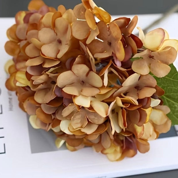 Artificial short dusky apricot hydrangea stem from Starlight Express, showcasing realistic faux flowers and lush green foliage.
