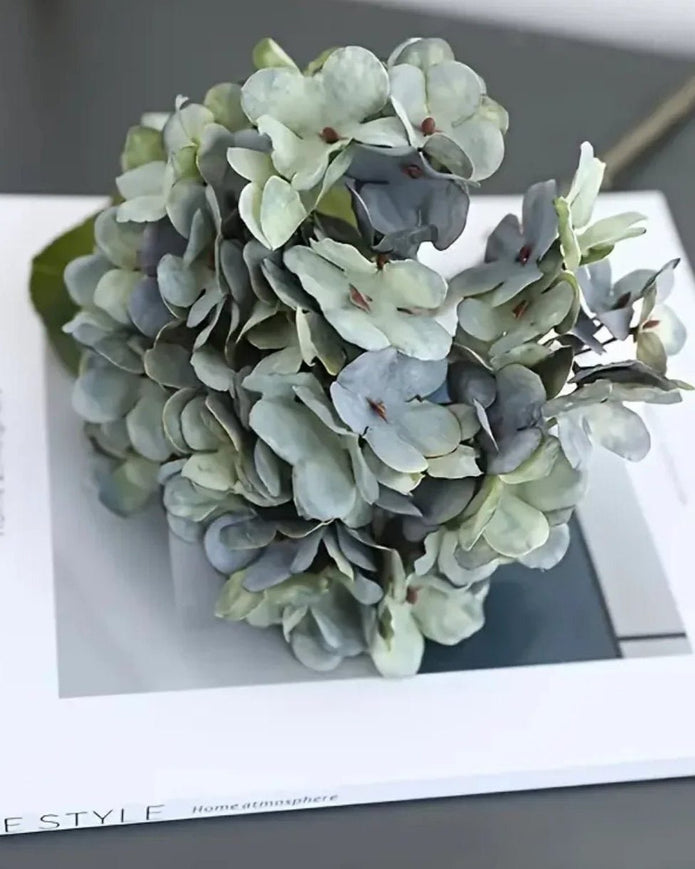 Artificial short dusky blue hydrangea stem from Starlight Express, featuring vibrant blue blooms and realistic foliage.