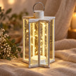 Cream Starlight lantern with warm lights styled on soft neutral fabric.