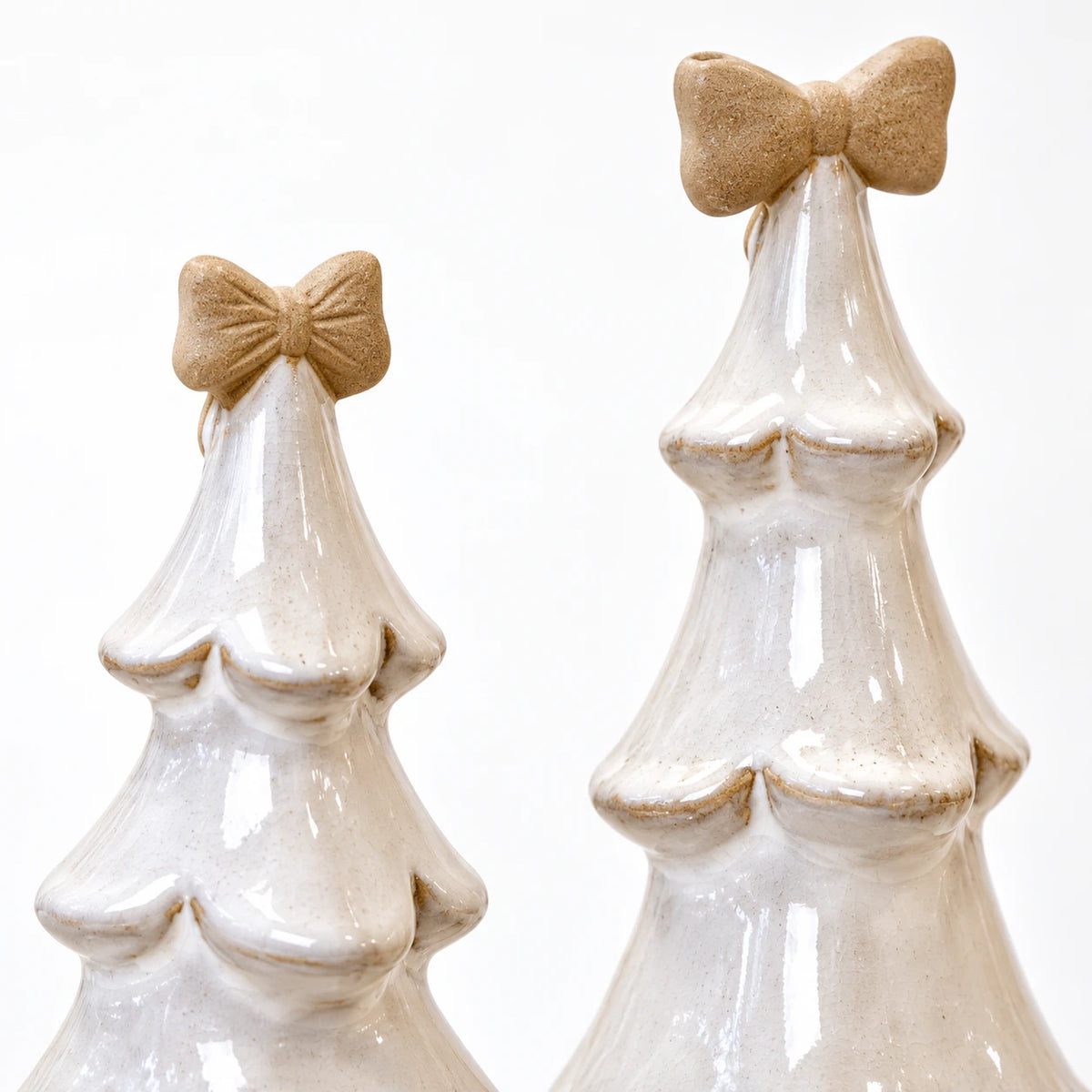 Medium and large stone-glazed ceramic Christmas trees with cream bows, showing a close-up of their ceramic bows and scalloped branches.