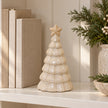 Neutral ceramic Christmas tree beside linen books on a shelf