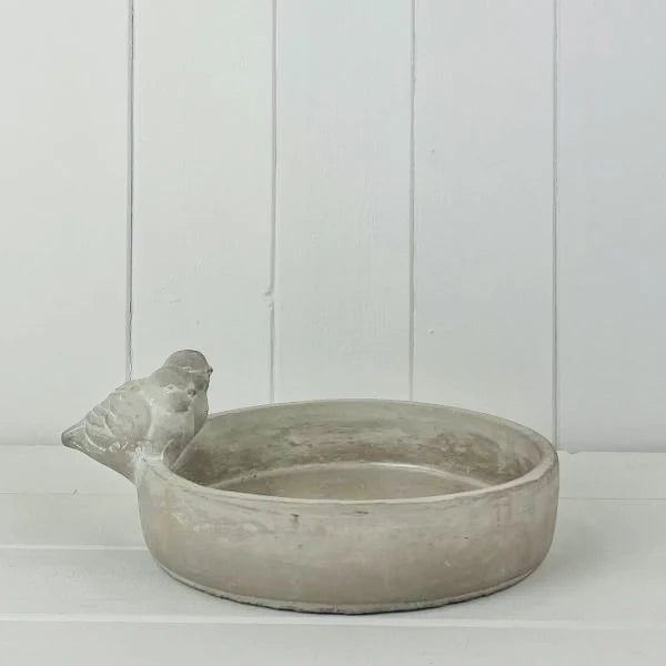 Stoneware bird bath bowl with sculpted bird on rim against a white studio background